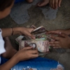 Billetes en desuso son el juguete de los niños en un pueblo de Venezuela