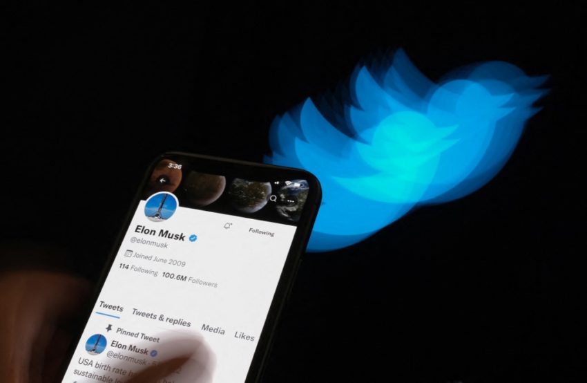 This illustration photo taken on July 8, 2022 shows Elon Musk's Twitter page displayed on the screen of a smartphone with Twitter logo in the background in Los Angeles. - Elon Musk pulled the plug on his deal to buy Twitter on July 8, 2022, accusing the company of "misleading" statements about the number of fake accounts, a regulatory filing showed. (Photo by Chris DELMAS / AFP)